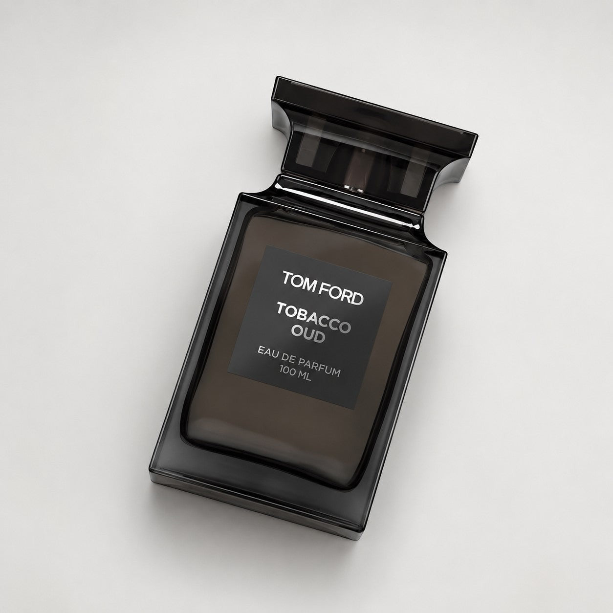 Frasco de perfume Tom Ford Tobacco Oud de Ricky Luxury en vidrio oscuro con etiqueta elegante sobre fondo neutro