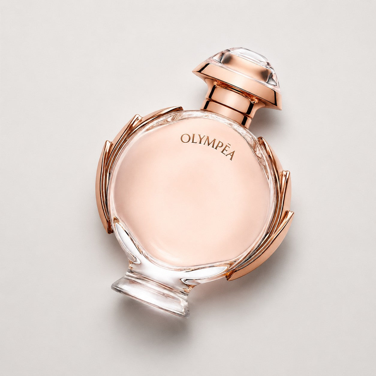 Frasco de perfume Paco Rabanne Olympea de Ricky Luxury con diseño circular en tono oro rosa y cristal transparente