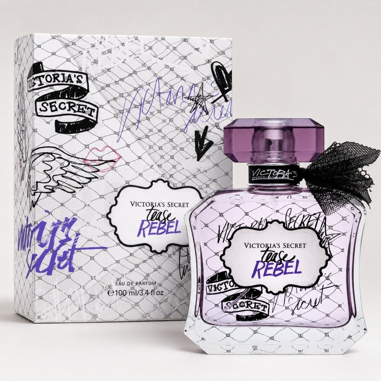 Perfume Victoria's Secret Tease Rebel de Ricky Luxury con frasco de cristal morado, lazo negro y caja decorada.