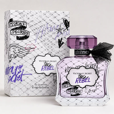 Perfume Victoria's Secret Tease Rebel de Ricky Luxury con frasco de cristal morado, lazo negro y caja decorada.