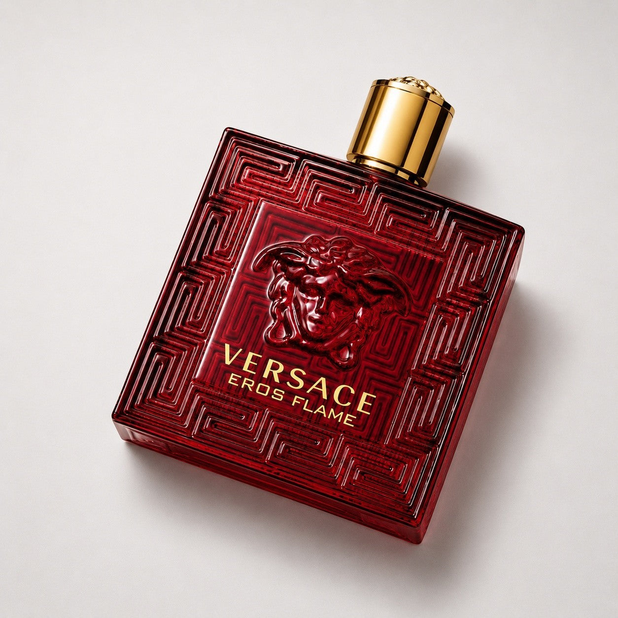 Frasco de perfume Versace Eros Flame de Ricky Luxury en cristal rojo intenso con relieve de Medusa y tapón dorado